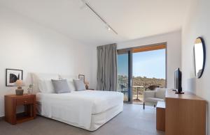 a white bedroom with a white bed and a television at Villa Euphoria in Paphos +67 photos