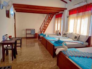 Habitación con 3 camas, mesa y comedor. en Hungry Lion Resort en Sigiriya