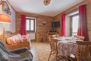 a living room with a dining room table with red curtains at 153 Rue des Rochers in Lanslevillard