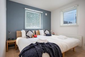 富良野的住宿－ArtHouse by H2 Life，卧室设有两张床,带两个窗户