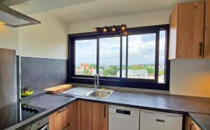 a kitchen with a sink and a large window at L'Appartement en Haut in Saint-Denis