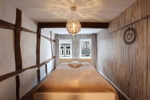 een slaapkamer met een bed met een kroonluchter bij Le cosy 40 - maison typique au centre de Malmedy in Malmedy