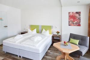 um quarto com uma grande cama branca e uma mesa em Wohlfühlhotel Frohsinn em Fischen