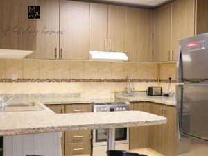 a kitchen with wooden cabinets and a stainless steel refrigerator at Mira Holiday Homes - Serviced 1 bedroom with Creek View in Dubai