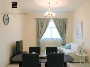 Mira Holiday Homes - Serviced 1 bedroom with Creek View في دبي: غرفة معيشة مع أريكة وطاولة وكراسي