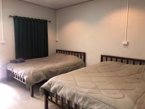 a bedroom with two beds and a green curtain at บ้านทองอาทรเขาค้อ in Khao Kho