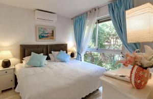 1 dormitorio con 1 cama con cortinas azules y ventana en Villa Picaud - 50M plage, terrasse, clim - Unique Centre Cannes en Cannes