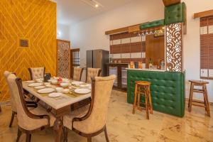 a dining room with a table and chairs and a kitchen at StayVista at SilverOaks Cottage in Dehradun