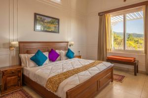 a bedroom with a large bed with blue and purple pillows at StayVista at SilverOaks Cottage in Dehradun