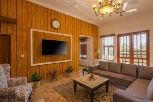 a living room with a couch and a clock on the wall at StayVista at SilverOaks Cottage in Dehradun