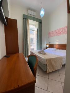 a bedroom with two beds and a table and a window at Hotel Eliseo Napoli in Naples