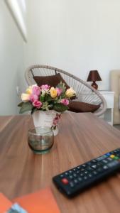 a vase of flowers on a table next to a remote control at Happy Star in Niš