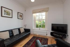 a living room with a black leather couch and a flat screen tv at Apartment 4 The Grove in Durham