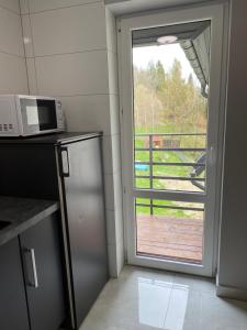 a kitchen with a microwave and a door to a balcony at Nocleg pod Turbaczem in Nowy Targ