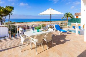 a patio with a table and chairs and an umbrella at Villa Proa in Son Bou