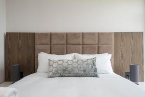 a bedroom with a large white bed with a brown headboard at 1 Licorna Beach in Durban