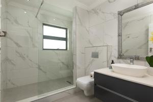 a bathroom with a shower and a sink and a toilet at 1 Licorna Beach in Durban +35 photos