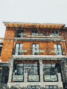 un bâtiment en briques avec de la neige tombant sur lui dans l'établissement Hotel Ailama Mestia, à Mestia