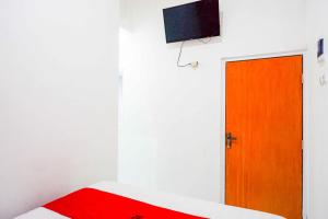 a room with a red door and a television at RedDoorz @ Kawasan Industri Candi Semarang in Kalibanteng-kidul