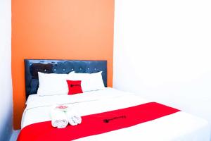 a bed with a red and white blanket and slippers at RedDoorz @ Kawasan Industri Candi Semarang in Kalibanteng-kidul