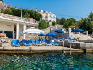 a group of blue chairs and umbrellas in the water at Apartments Rašica Molunat in Molunat