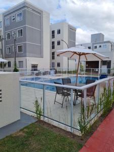 a table with an umbrella next to a swimming pool at Ao lado do shopping com piscina e ar condicionado. in Caruaru