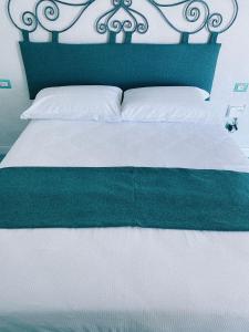 uma cama com uma cabeceira verde e lençóis brancos em Lavinum em Monte di Procida
