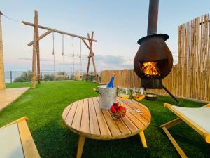 een picknicktafel met wijnglazen en een vuurplaats bij נוף המצוק in Poriyya