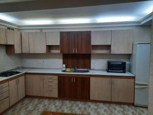 a kitchen with wooden cabinets and a sink and a refrigerator at Compleks Hostel of Nizami street in Baku