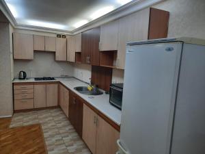 a kitchen with wooden cabinets and a white refrigerator at Compleks Hostel of Nizami street in Baku