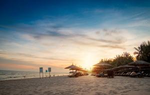 - un coucher de soleil sur une plage avec des parasols et l'océan dans l'établissement Bamboo Village Beach Resort & Spa, à Mui Ne