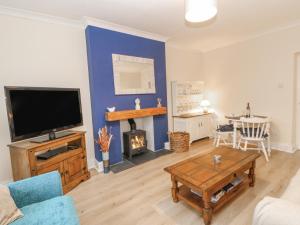 a living room with a tv and a couch and a table at Elm Cottage in Bishop Auckland