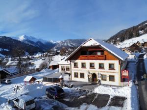 a building in the snow with mountains in the background at Hotel Die Metzgerstubn in Sankt Michael im Lungau