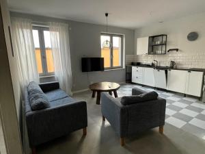 a living room with two couches and a table and a kitchen at Apartamenty Komorniki in Komorniki