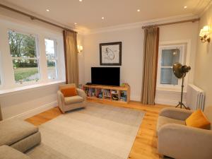 a living room with a tv and a couch and chairs at Knockanboy House in Ballymoney