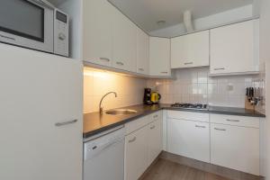 - une cuisine blanche avec des placards blancs et un évier dans l'établissement Residence Juliana appartement 53 -Julianadorp aan zee, à Julianadorp