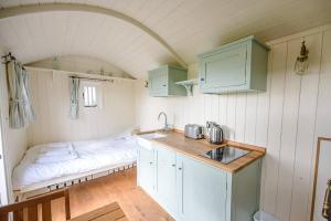 uma cozinha com uma cama e um lavatório num quarto em Sage Shepherds Hut Boundary Farm Air Manage Suffolk em Woodbridge