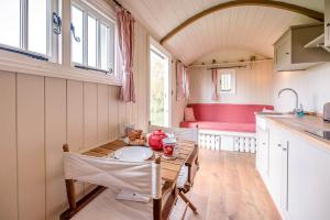 a small kitchen with a table and a bench at Thyme Shepherds Hut Boundary Farm Air Manage Suffolk in Woodbridge