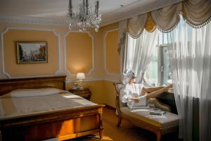 Una donna seduta su una sedia in una camera da letto di Grand Hotel Emerald a San Pietroburgo