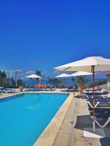 una piscina con sombrilla y sillas en Hotel Marola, en A Lanzada