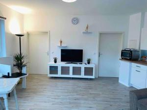 a living room with a television on a white cabinet at Schönes Bungalow, Check-In Kontaktlos, Zentral in Duisburg