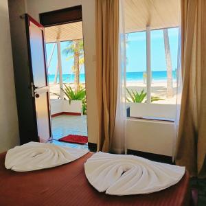 a bedroom with a bed with a view of the beach at French garden Pragash Beach Hotel in Trincomalee