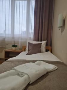 uma cama branca com uma almofada e uma janela em Garni hotel Alma em Pirot