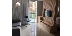uma sala com uma TV, um sofá e uma cadeira em Aluga-se por temporada em Vitória