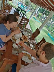 a group of people sitting at a table eating food at Evergreen Villa - Sinharaja in Deniyaya