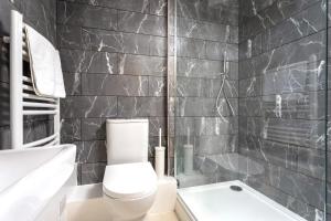 a black tiled bathroom with a toilet and a sink at Curb Properties - Cool Trendy Montpellier Apartment in Cheltenham