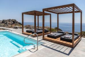 ein Pool mit zwei Liegen am Meer in der Unterkunft Pristine Seaview Villa , with 5-Star Resort Access in Faliraki