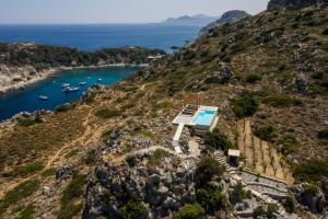 eine Insel mit einem Haus auf einem Hügel mit einem Pool in der Unterkunft Pristine Seaview Villa , with 5-Star Resort Access in Faliraki