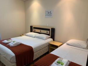 a hotel room with two beds and a table at Hotel Tropeiro da Lapa in Lapa