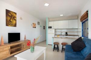 a living room with a blue couch and a kitchen at Apartamento Mirra - Beach view in Puerto Rico de Gran Canaria